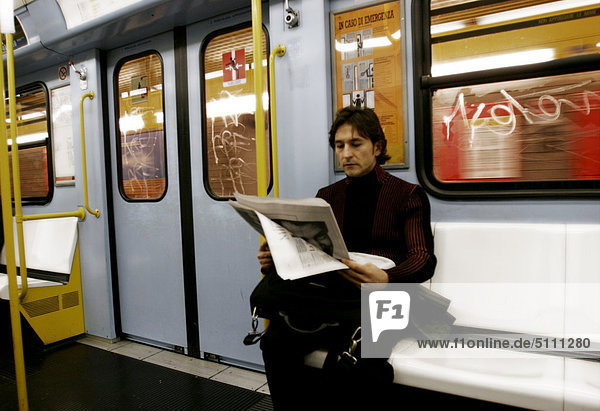 Man reading newspaper in subway