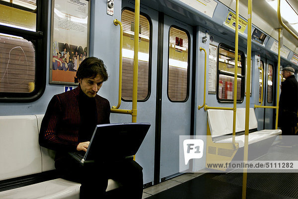 Mann mit Laptop auf u-Bahn