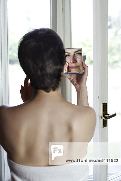 Frau blickt auf selbst im Spiegel