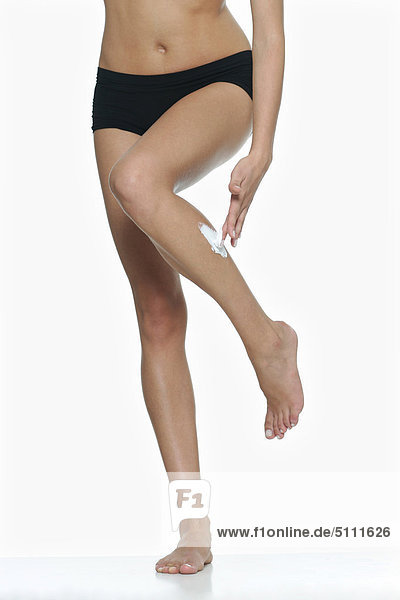 Woman applying Feuchtigkeitscreme auf Bein