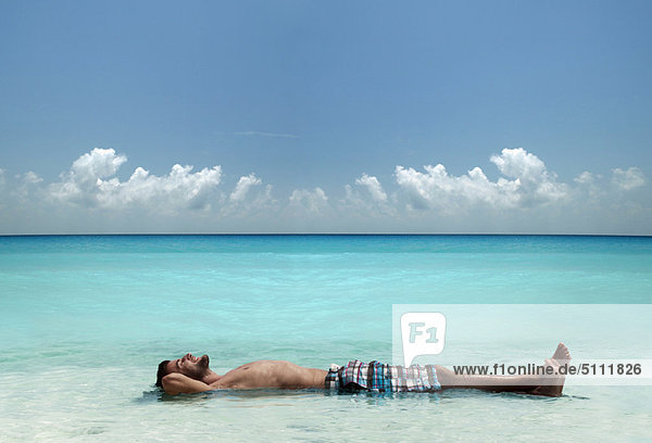 Man floating in water at tropical beach
