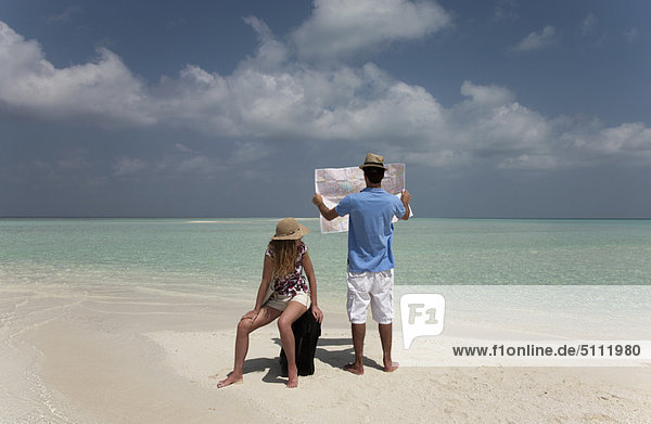 Couple reading map on tropical beach
