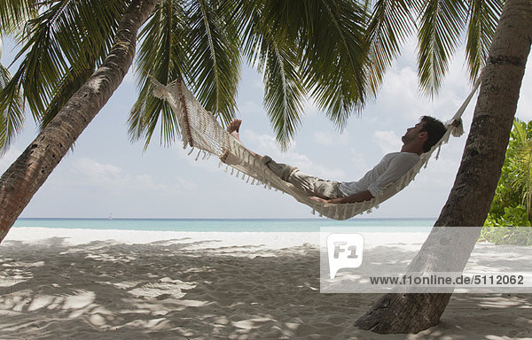 Man laying in hammock on beach