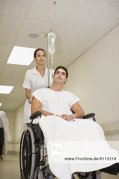Krankenschwester schiebt Patient im Rollstuhl