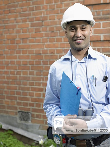 Businessman in hard hat carrying folder