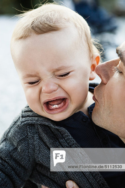 Vater küssend weinendes Baby