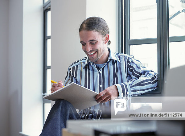 Lächelnder Geschäftsmann beim Schreiben im Büro