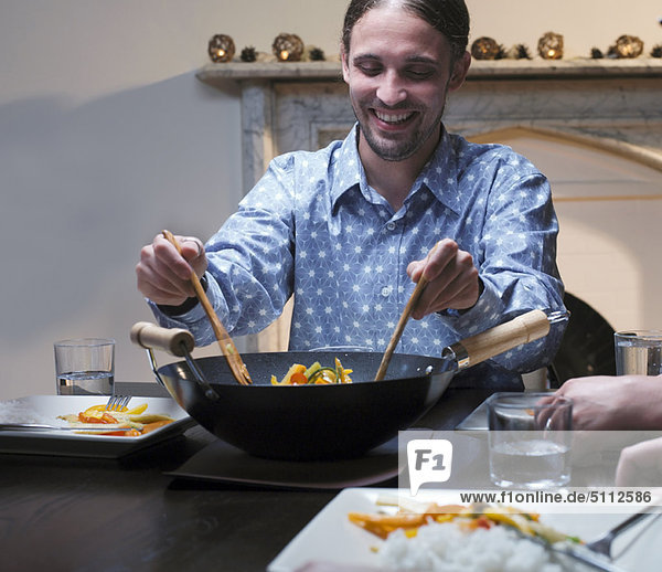 Mann serviert Abendessen aus dem Wok