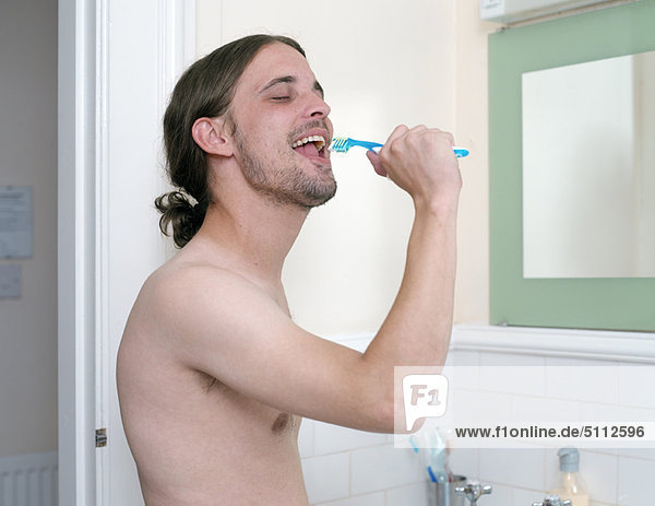 Mann beim Zähneputzen im Bad