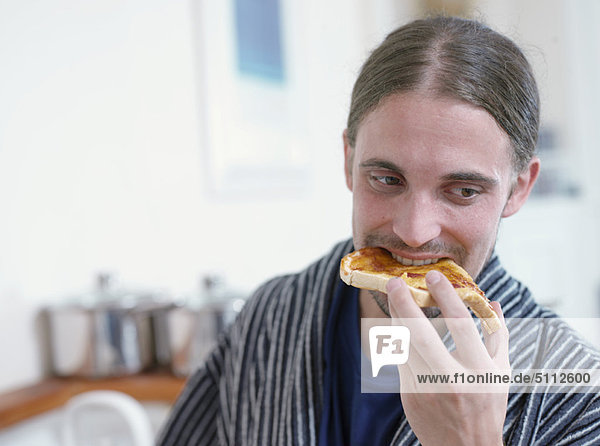 Man eating toast in kitchen