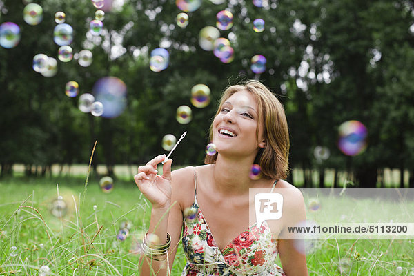 Woman blowing bubbles in field