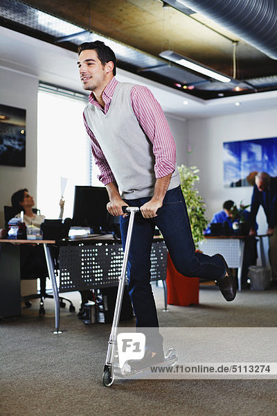 Businessman riding scooter in office