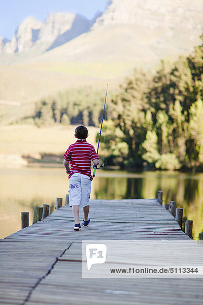 Junge - Person  über  See  Steg  angeln  Stange