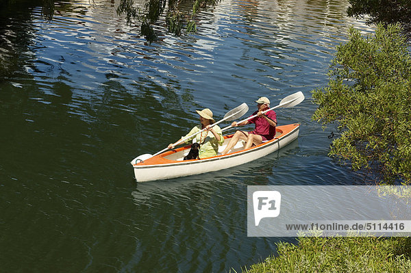 Older couple rowing canoe on lake