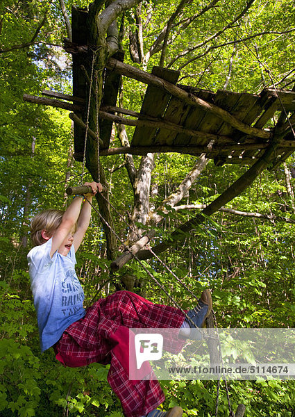 Boy climbing rope ladder in tree house
