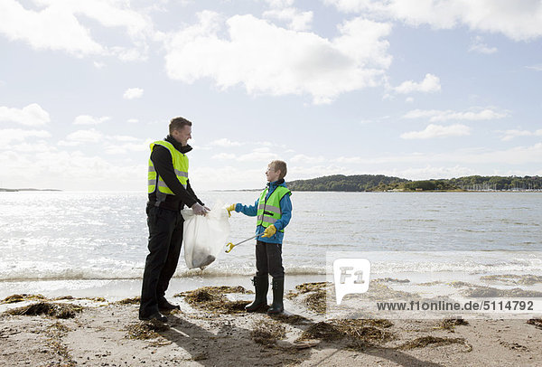 Father and son cleaning beach