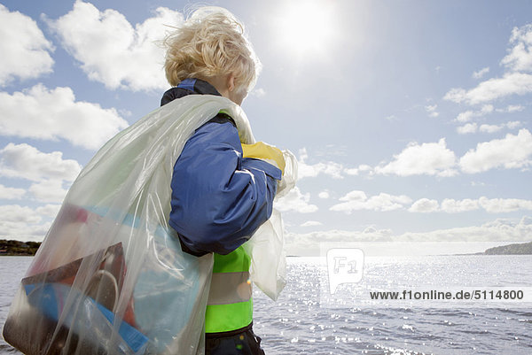 Boy hauling bag of trash on beach