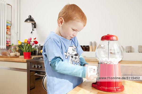 Junge mit Gummiballmaschine in der Küche