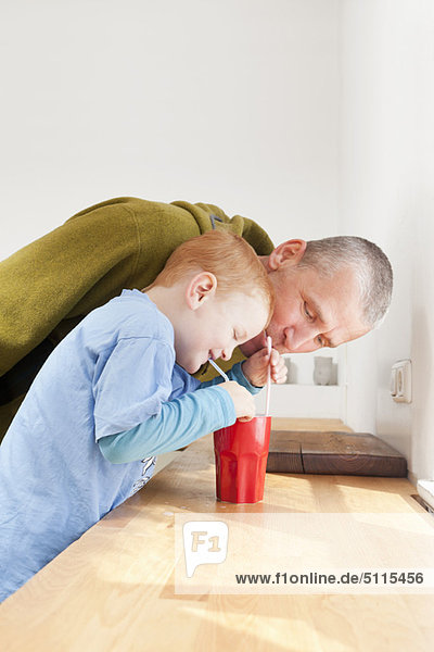 Vater und Sohn trinken mit Strohhalmen