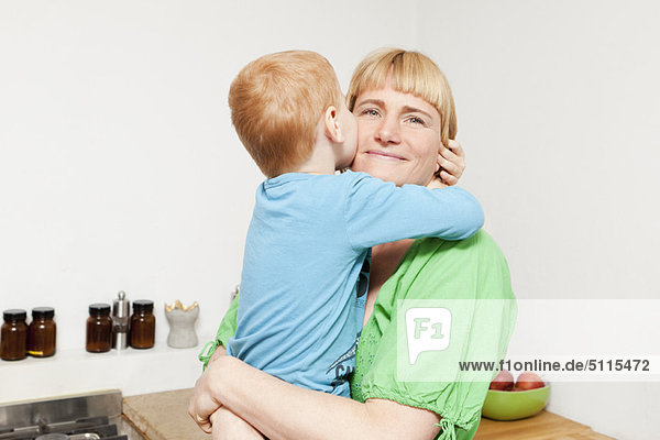 Mutter und Sohn umarmen sich in der Küche