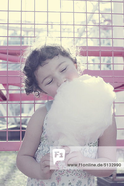 Little girl enjoying cotton candy with eyes closed