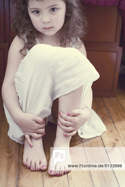 Kleines Mädchen im Kleid  Knie umarmend  Porträt