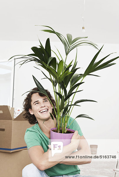 Junger Mann mit Topfpflanze bei der Renovierung der Wohnung