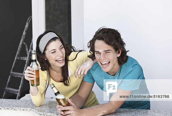 Deutschland  Köln  Junges Paar trinkt Bier in der Wohnung