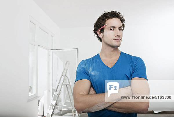 Junger Mann mit Bleistift hinter dem Ohr in renovierender Wohnung  Portrait