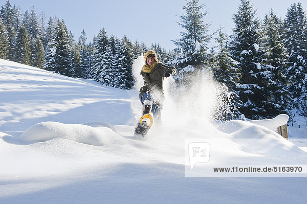 Österreich  Salzburger Land  Flachau  Junge Frau mit Schneeschuhen beim Wandern im Schnee