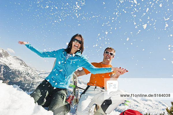 Österreich  Salzburger Land  Altenmarkt-Zauchensee  Mittleres erwachsenes Paar im Winter im Schnee sitzend und Spaß habend