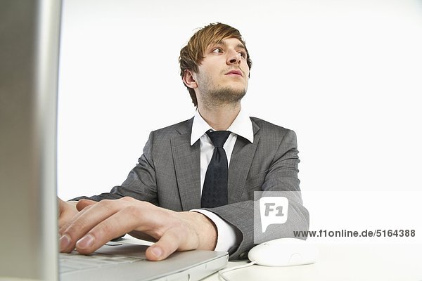 Young businessman working on laptop against white background