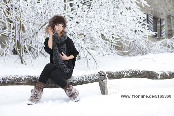 Junge Frau mit Schal und Mütze im Schnee