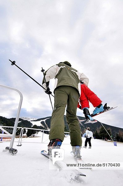 Skiers  man carrying a child. La Molina ski resort  Cerdanya  Girona province  Catalonia  Spain