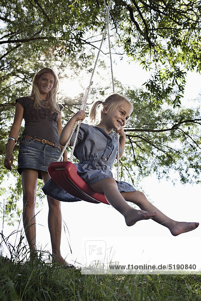Mother pushing daughter on swing