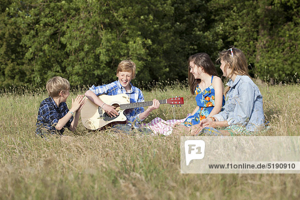 Children playing music together in field