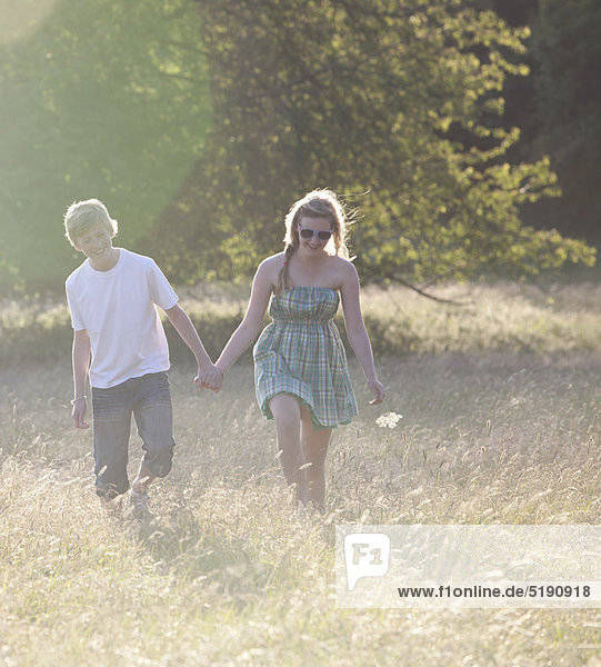 Teenage couple walking together in field