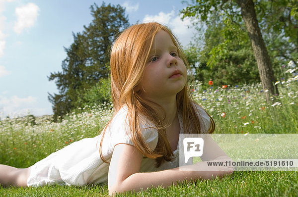 Girl laying on grass in field of flowers