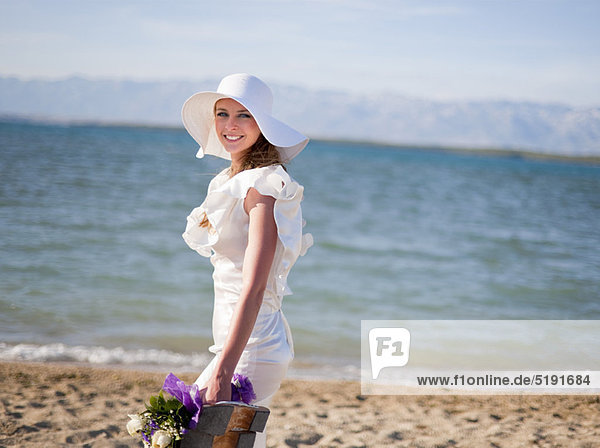 Bride carrying bouquet on beach