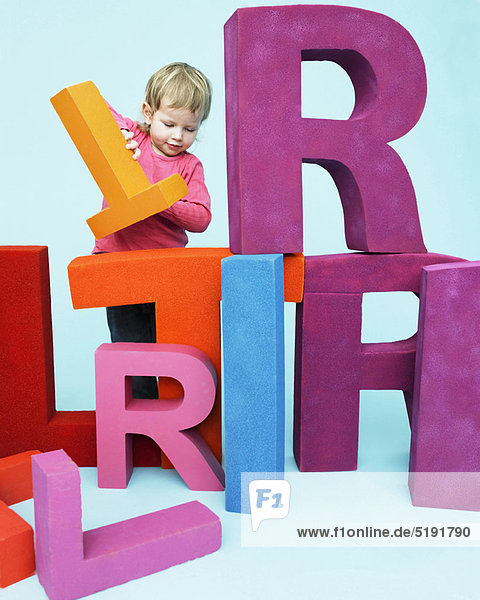 Kleinkind spielt mit übergroßen Buchstaben