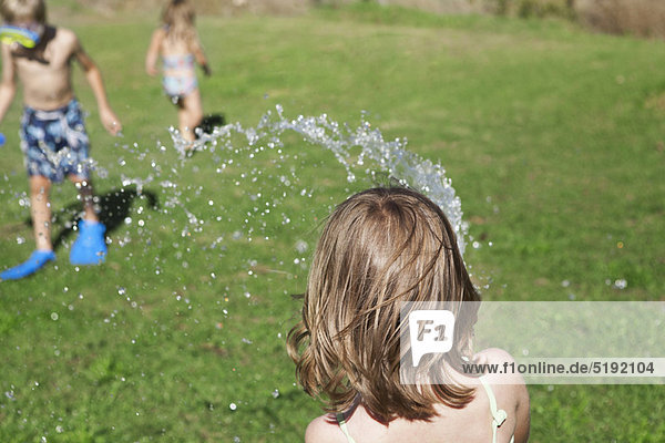 Children playing with hose in backyard