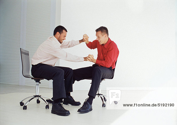 Businessmen playing in office chairs