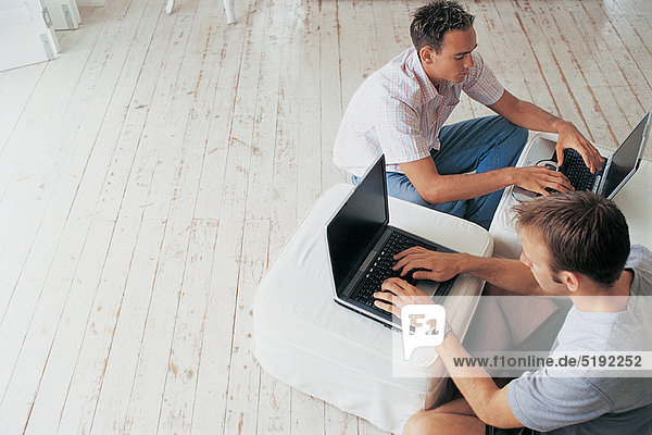 Men using laptops in living room