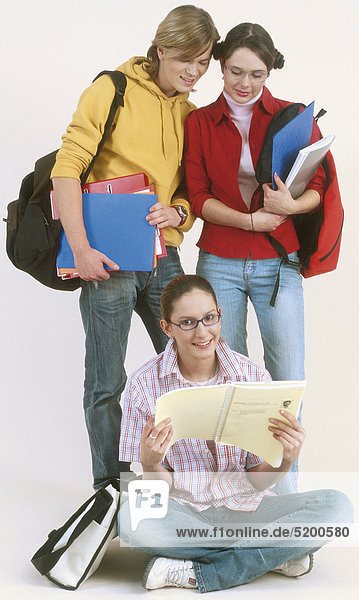 Drei Jugendliche Schülerinnen Und Schüler  Eine Sitzt am Boden