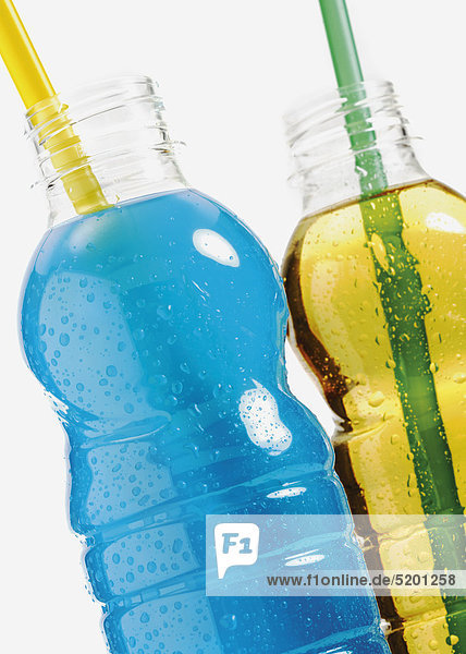 Zwei Plastikflaschen mit farbigen Energydrinks  Strohhalme