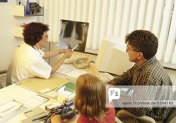 Ärztin erklärt Vater und Tochter ein Röntgenbild
