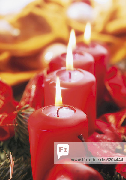 Vier brennende  rote Kerzen in Weihnachtsdekoration