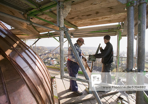 Spengler  Meister und Lehrling arbeiten an Kupferdach eines Kirchturms
