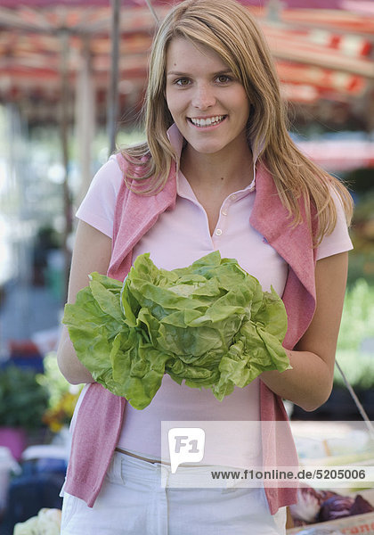 Junge Frau mit Salatkopf am Markt
