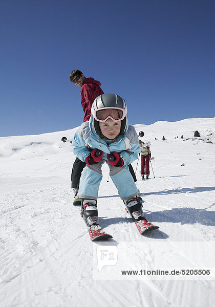 Familie beim Skifahren  kleines Mädchen fährt Vater durch die Beine